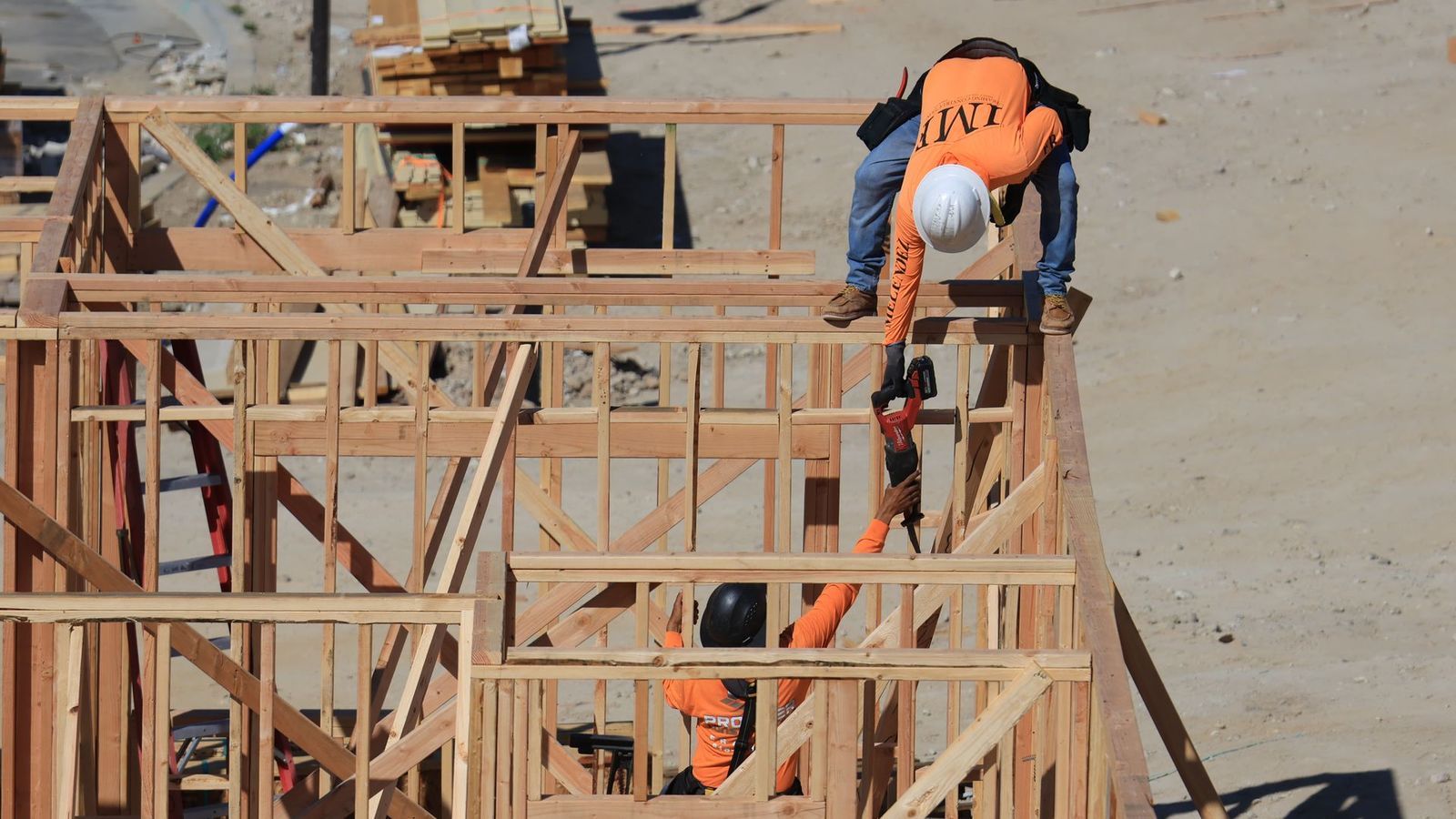 Two carpenters framing a wood structure on a residential construction site