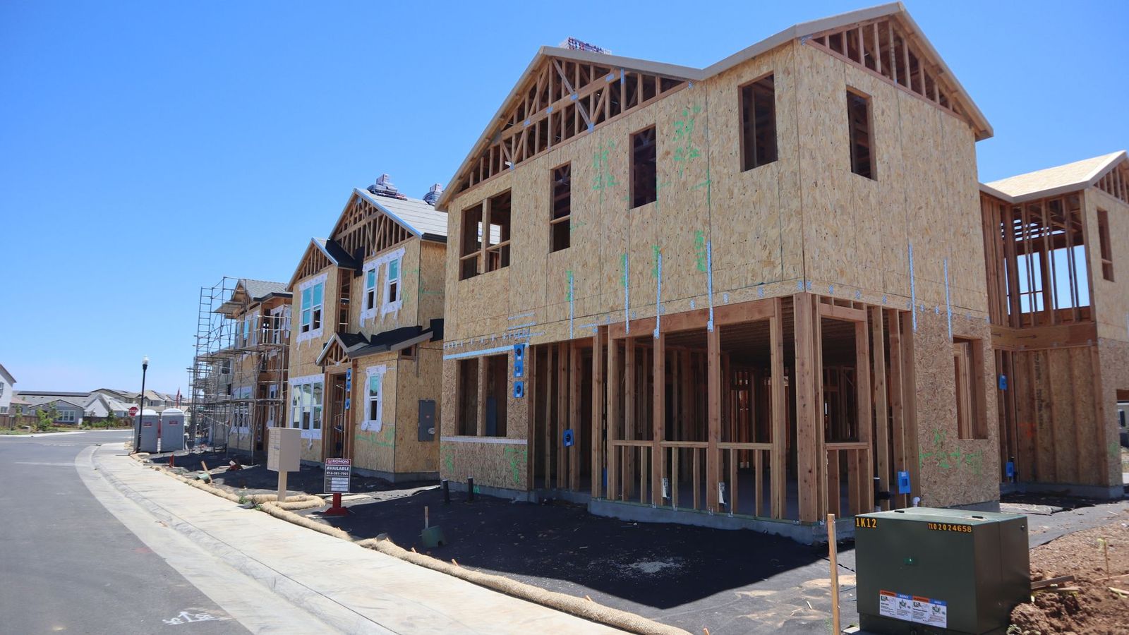 Wood framing for new homes under construction against a clear blue sky